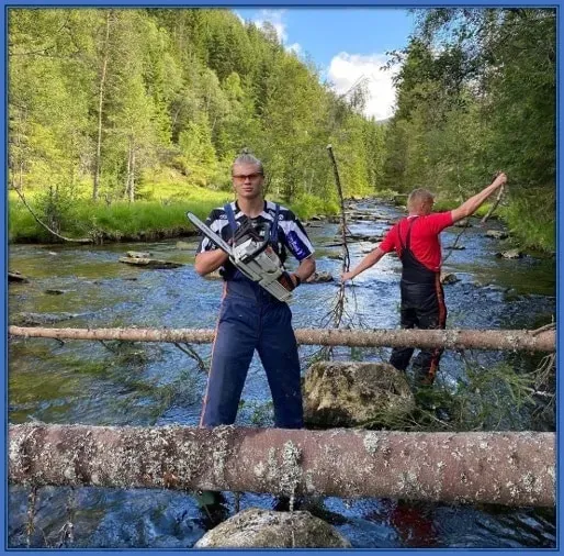 Erling Haaland is pictured with a chain saw wood cutting machine attempting to cut trees. His Dad (Alf-Inge Håland) is pictured behind him.