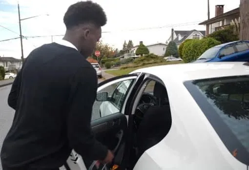 A rare photo of the winger trying to take his bag pack from the back of a car predicted to be an Audi. Image Credit: Spox.