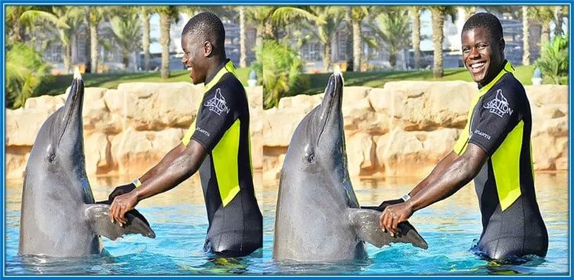 Malang Sarr plays with a dolphin like his pet.