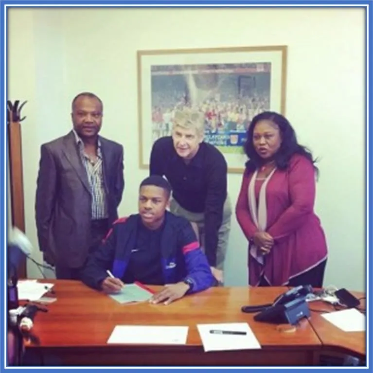 Here, Chuba Akpom&rsquo;s parents pose for the camera with him during his professional paper signing at 16.
