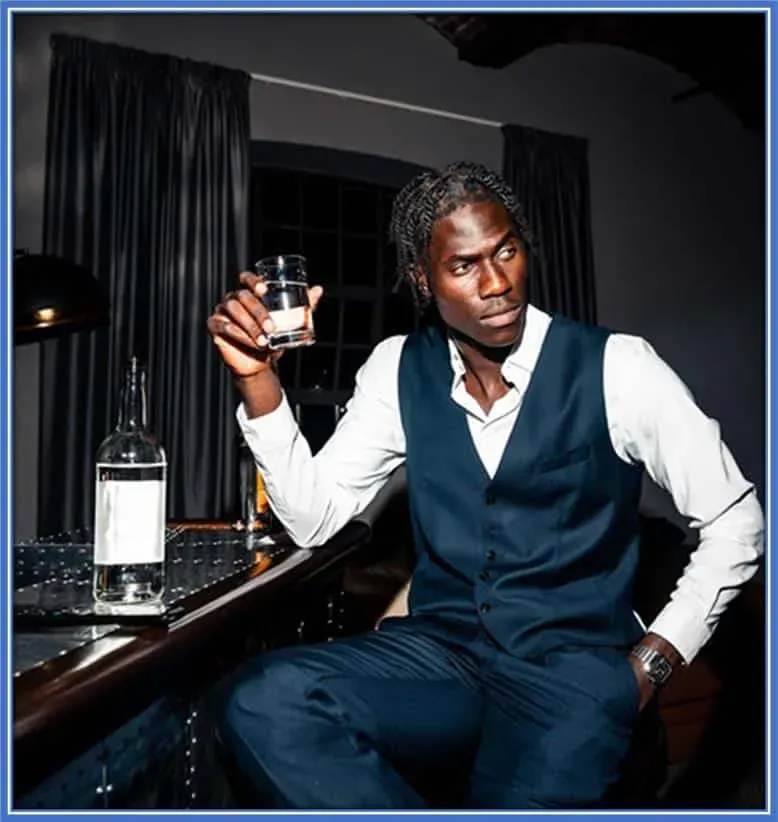 He has this Savoring Simplicity to his nature. Here, he takes a quiet moment to unwind with a glass of wine, embracing life's simple pleasures amidst his thriving football career.
