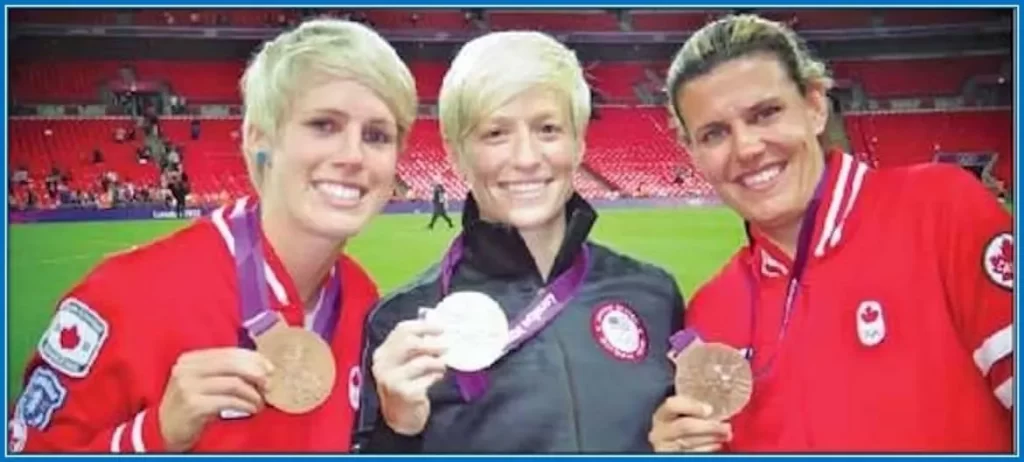 See the Legends- Megan and Christine Sinclair showcasing their medals with a teammate.