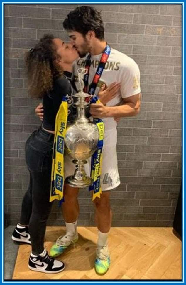 The Belgian holds his trophy as he shares a kiss with his girlfriend.