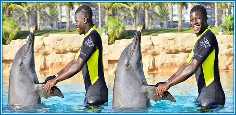 Malang Sarr plays with a dolphin-like pet.