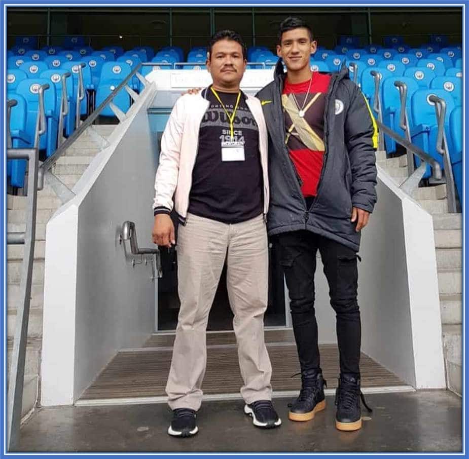 Carlos and his son pose for a photograph at a stadium.