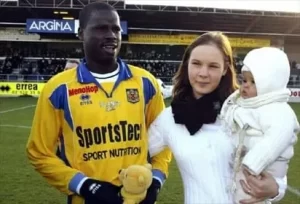 Aurélie and Eboue pose for a photo with their child.