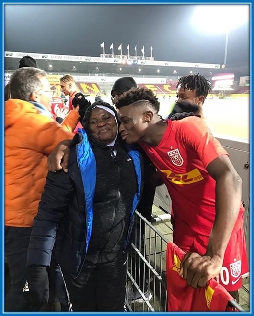 Mariama hugs and takes a photo with her son after a football match.