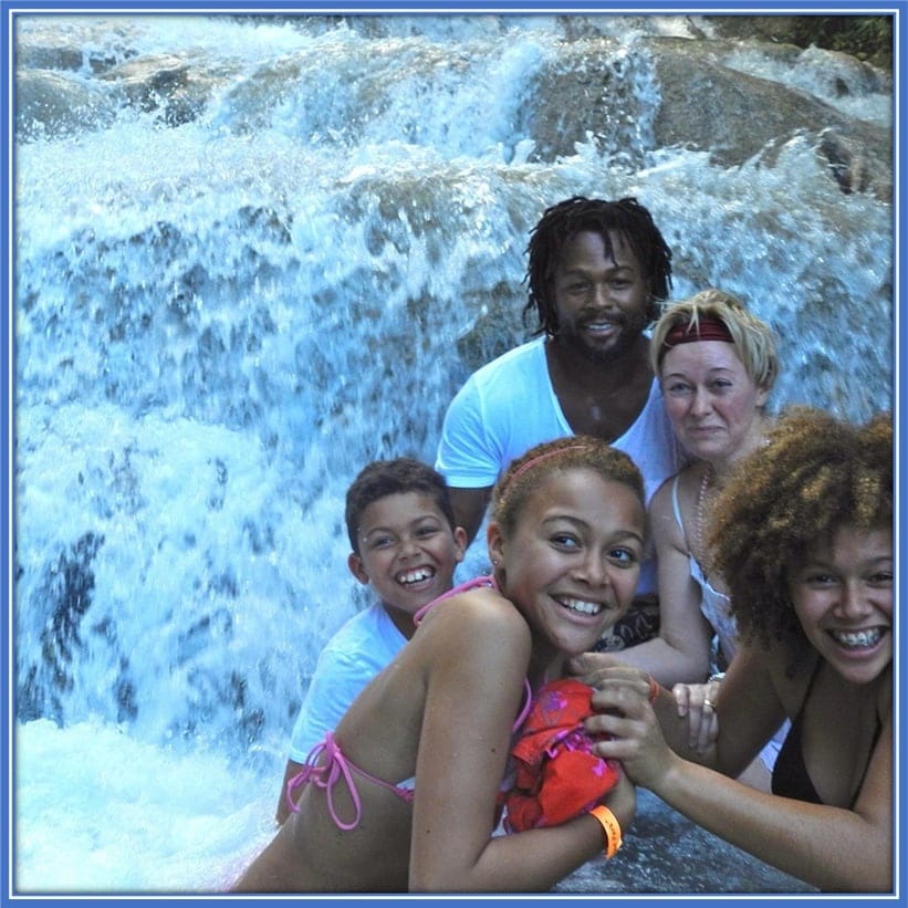 Introducing Brennan Johnson's Family. In the front row includes his sisters (Maddie and Liberty). Brennan is behind and we can see his parents (David and Alison). They all look very happy while enjoying a waterfall vacation.