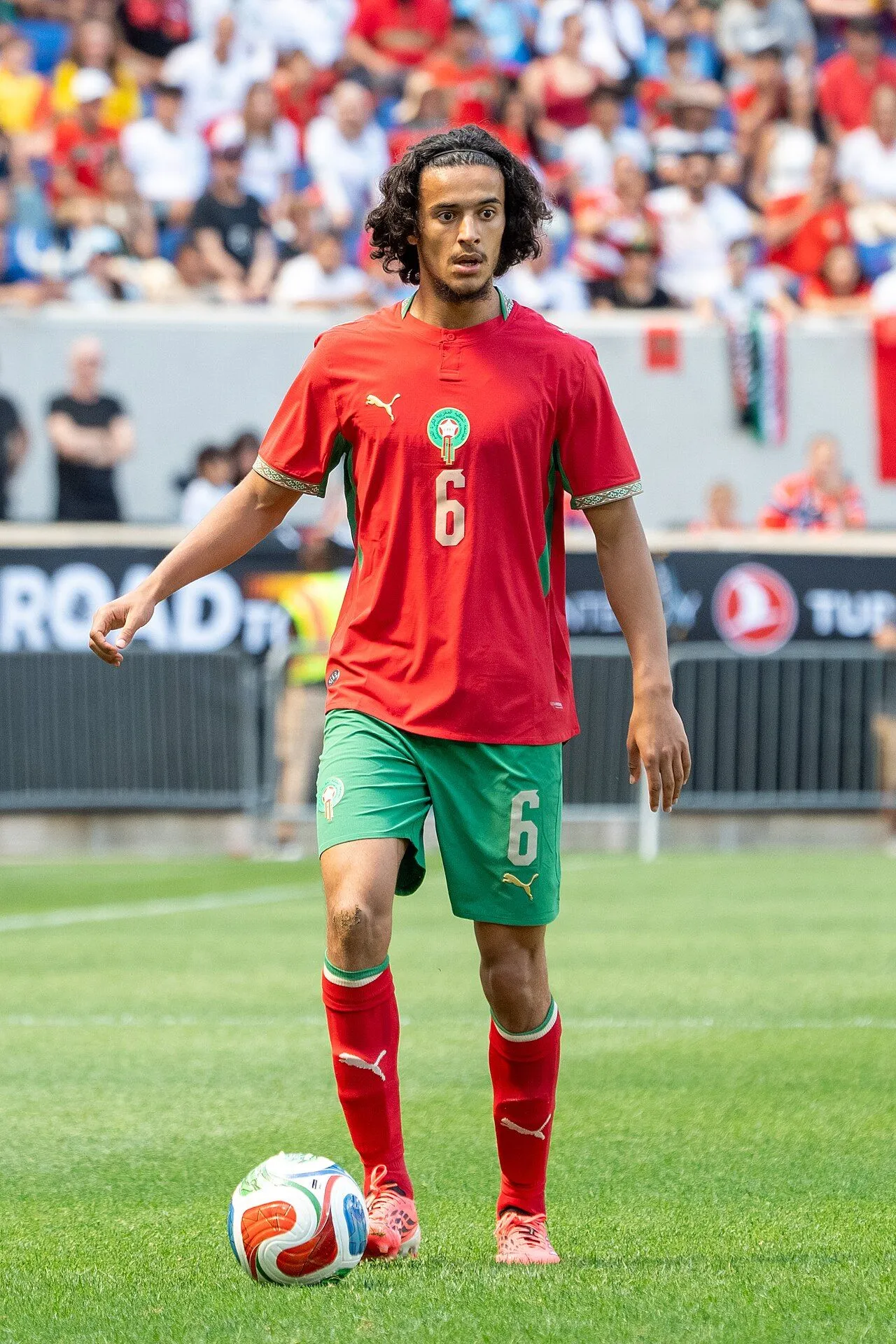 Young footballer controlling ball during training session on professional pitch