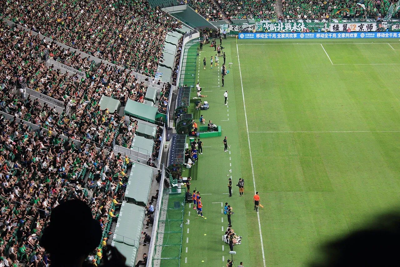 Chinese Super League goalkeeper making a diving save in a packed stadium