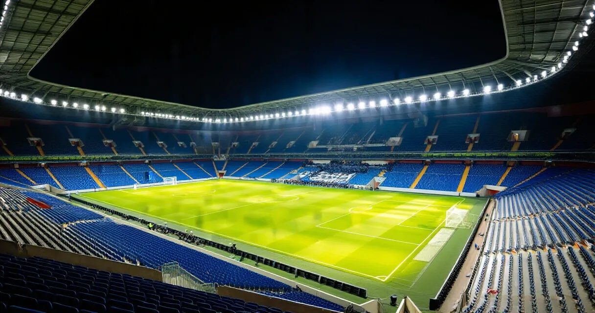 Professional footballer dribbling at speed on a European stadium pitch under floodlights
