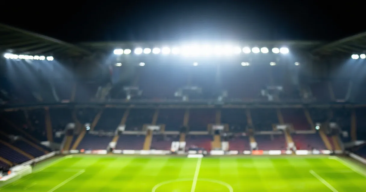 Packed football stadium at night with fans in red jerseys under bright floodlights