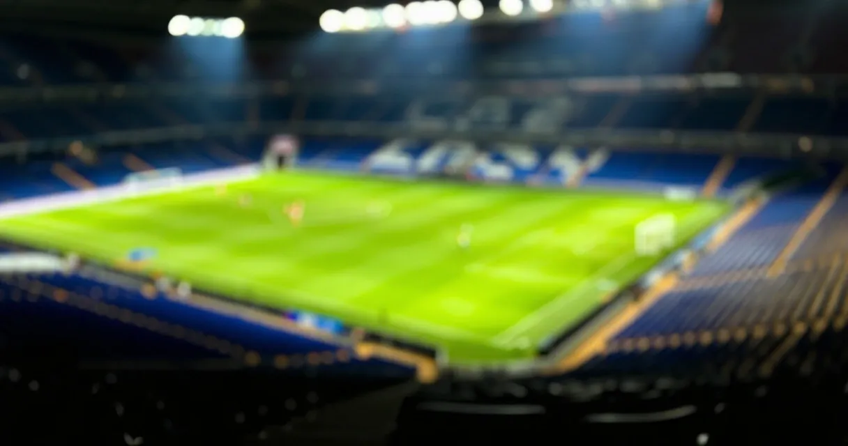 Calciatore professionista in allenamento su campo da gioco europeo, luci dello stadio sullo sfondo