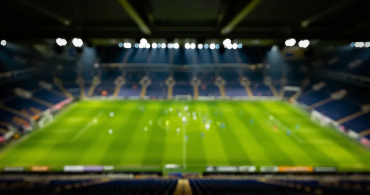 Football stadium at night with illuminated green pitch, no text visible