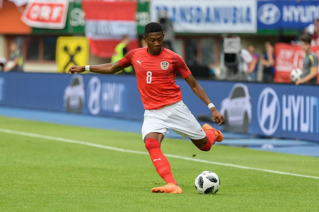 Football defender walking on pitch in packed European stadium