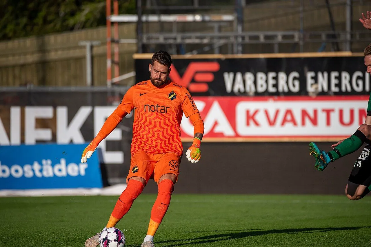 Veteran goalkeeper in yellow jersey on floodlit stadium pitch during match