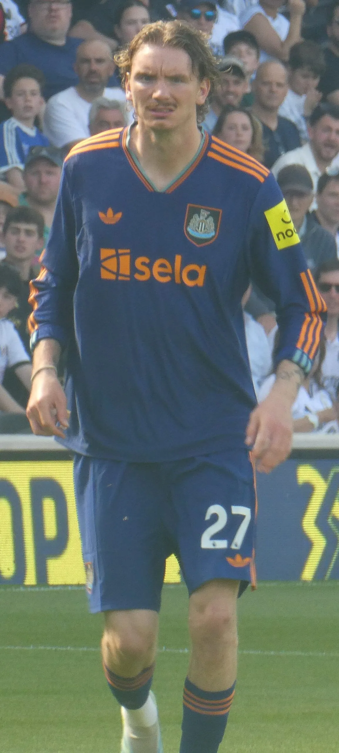 Football striker in black and white striped jersey running under stadium lights