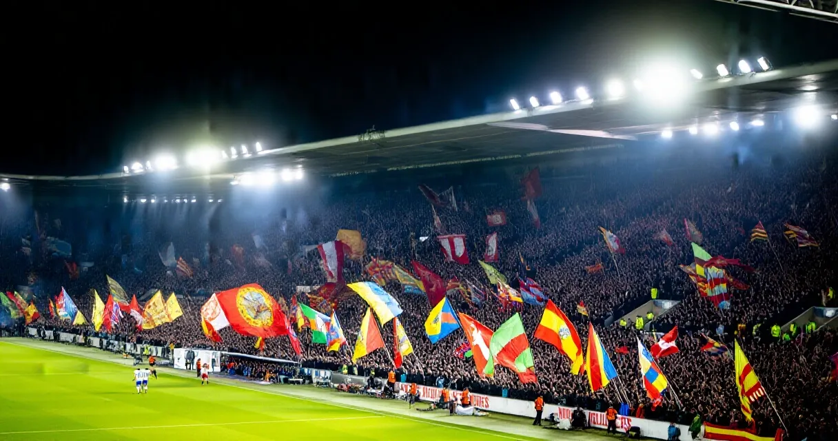 Torcida lotada assiste a partida de futebol inglês sob luzes de estádio à noite