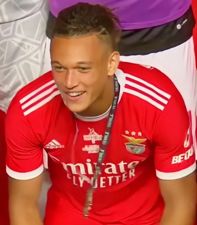 Footballer in red and black celebrating a goal in a packed stadium