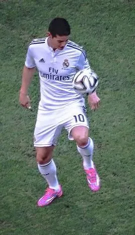 Football player in green jersey entering a packed South American stadium