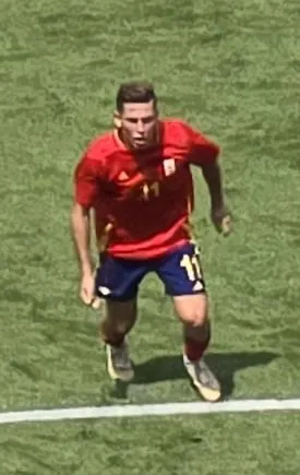 Midfielder celebrating a goal in a packed stadium under floodlights