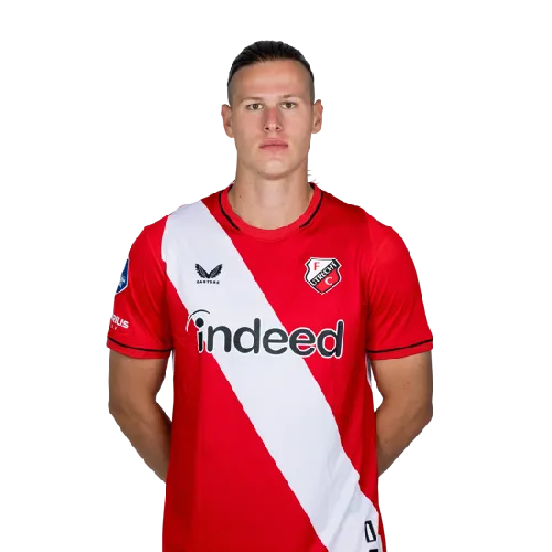 Voetballer viert een doelpunt op het veld terwijl fans op de tribune juichen